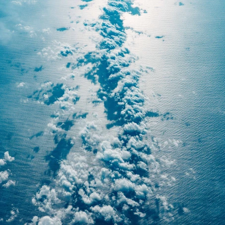 image taken from above of many clouds that are low over the ocean