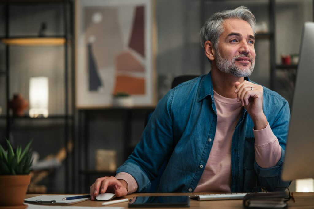 Mature man architect working on computer at desk indoors in office